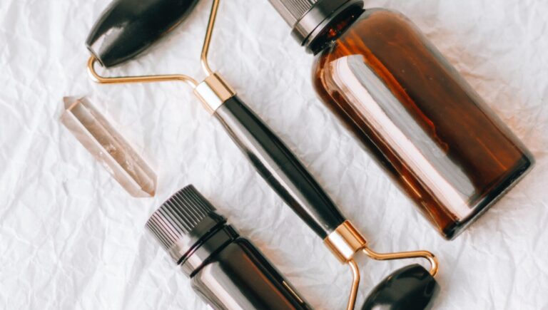 photo of a anti-aging serum bottle and an essential oil bottle along side a jade roller with a cream background