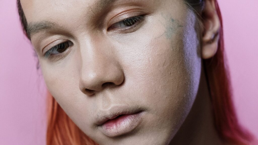 woman looking into a mirror with her face concealed with makeup concealer brush