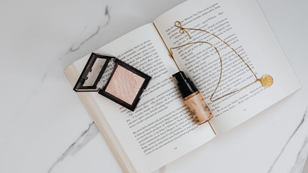 a bottle of makeup foundation and a concealer on an open book