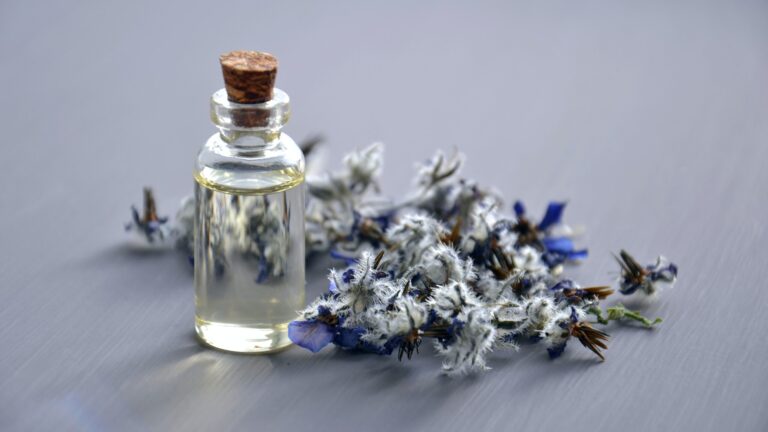 lavender flowers alongside a bottle of lavender essential oil