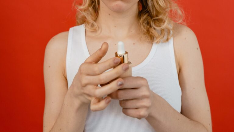 woman looking at a product that help prevent eyes to water because of applying makeup, posing in front on a red background