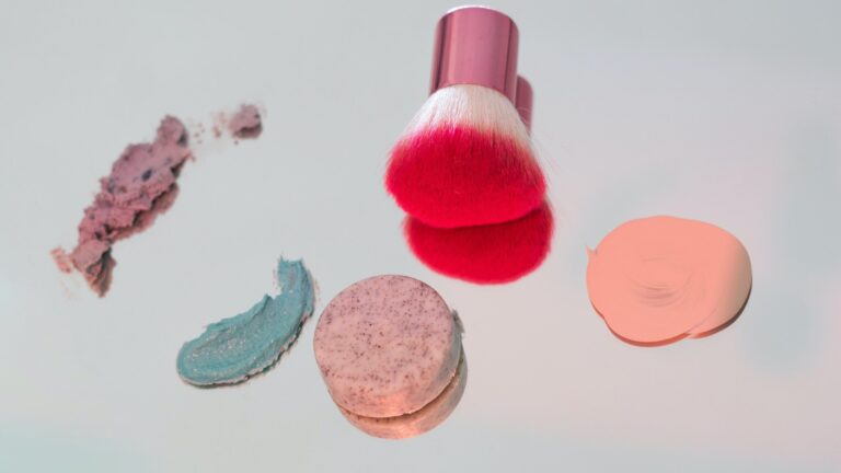 foundation and color correctors placed on a mirror besides a pink brush that helps with foundation separation at the nose