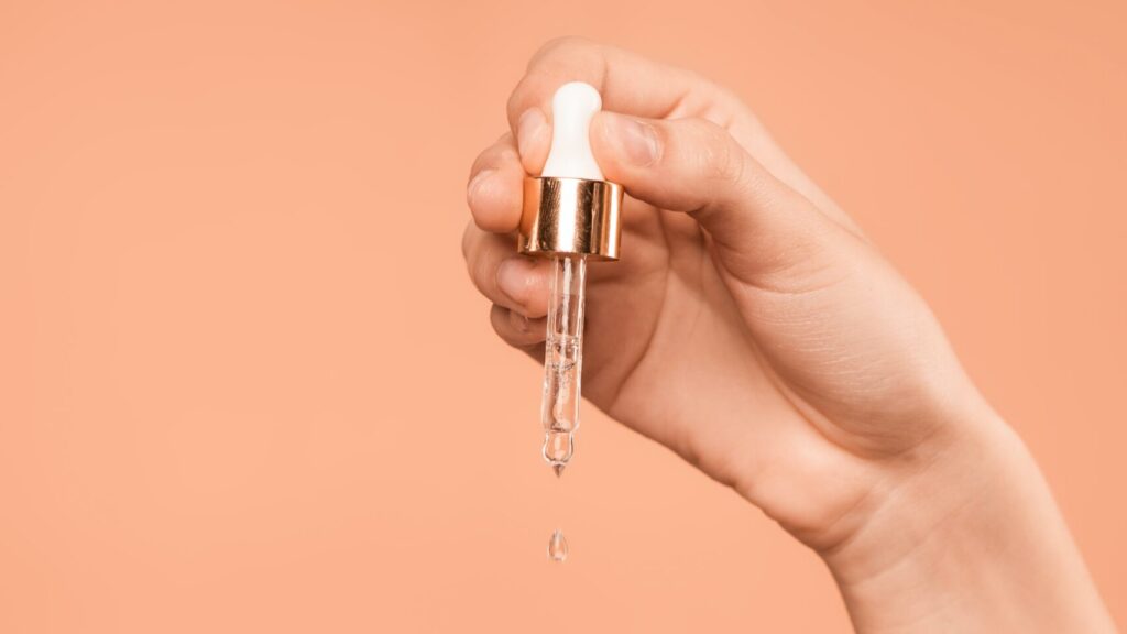 woman pouring vitamin c serum with a dripper