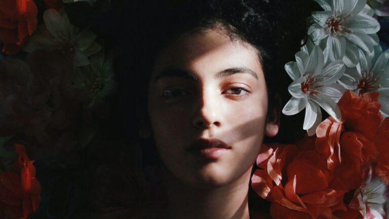 woman posing in front of a camera with white flowers on her right side, showing what look mixing foundations can help achieve