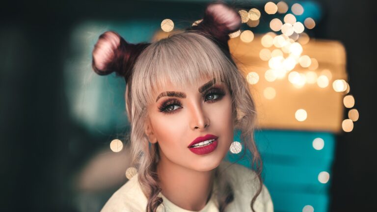 a woman with salt and pepper hair standing in front of a colorful background as she has brown eyeshadow on