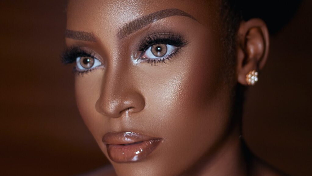 an afro woman posing for a photo as she has makeup on and glossy lips