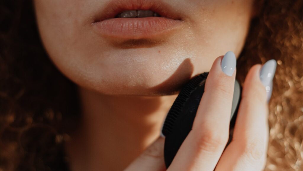 woman applying makeup on her face with a beauty blender