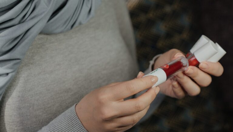 a woman in grey clothes holding Glitter lip gloss