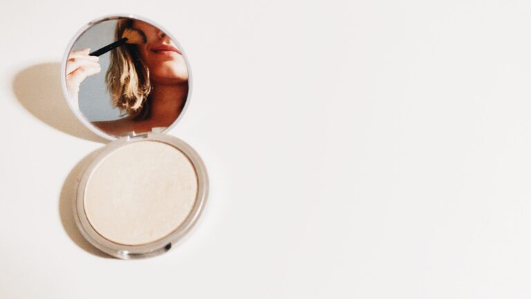 a woman looking into a mirror applying mica powder