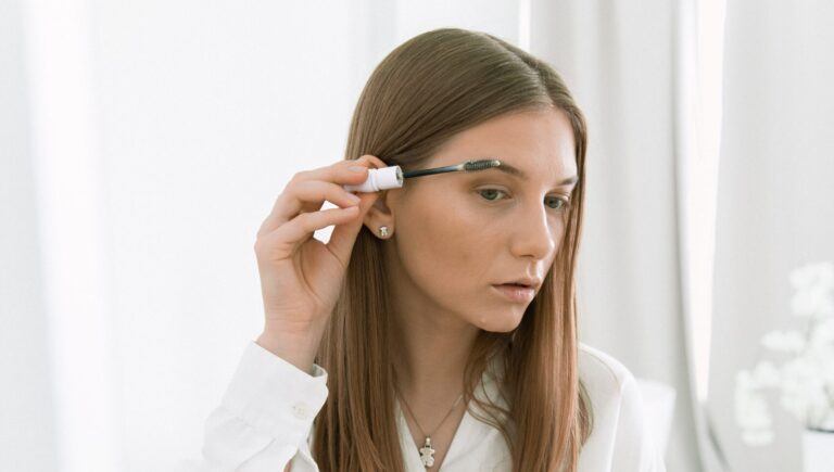 woman in a white shirt using mascara as an eyebrow filler