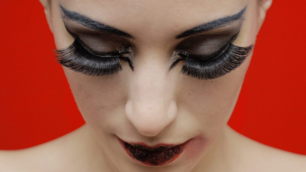 woman showing her eyelash extensions with mascara and bold makeup