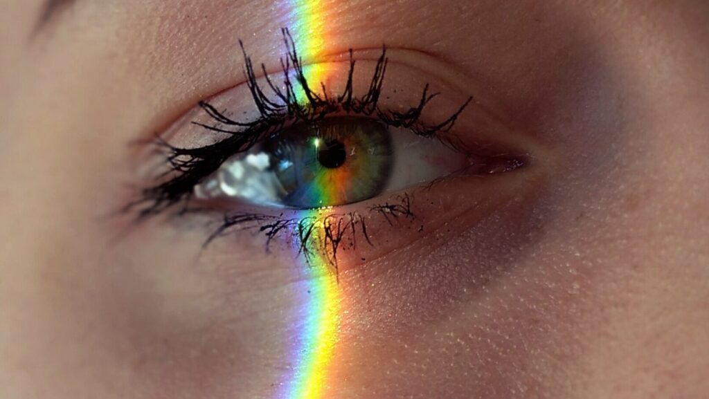 close up of a womans eye with rainbow lights going through