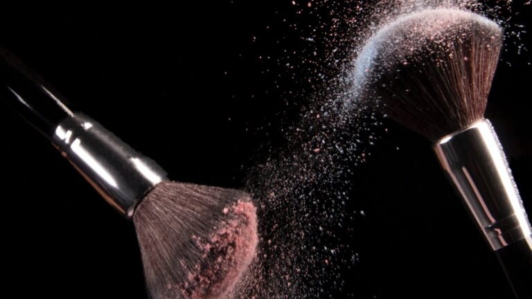 two brushes dusting off makeup products, either a concealer or face powder