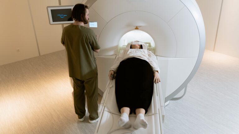 a woman going user an MRI machine, as a nurse in green scrub stands besides her