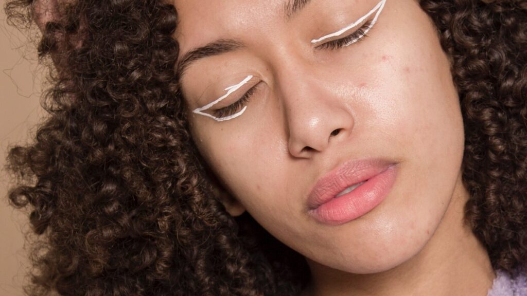 woman with curly hair showing her white permanent eyeliner