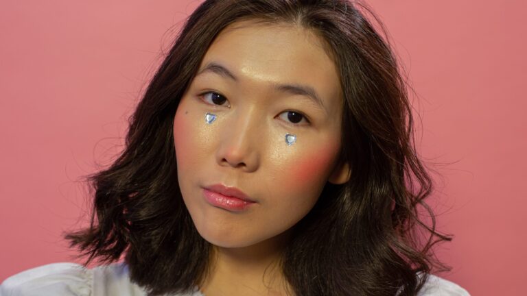 a woman posing with pink lip gloss as she poses in front of a pink background