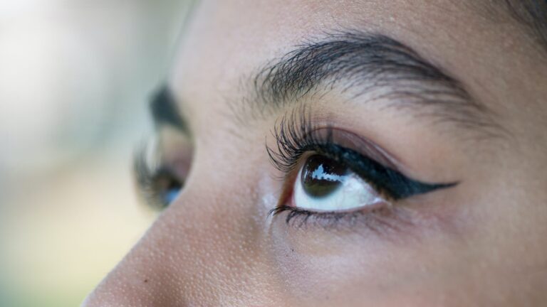 an indian woman showing her black colored eyeliner drawn with eyebrow pencil as he looks up.