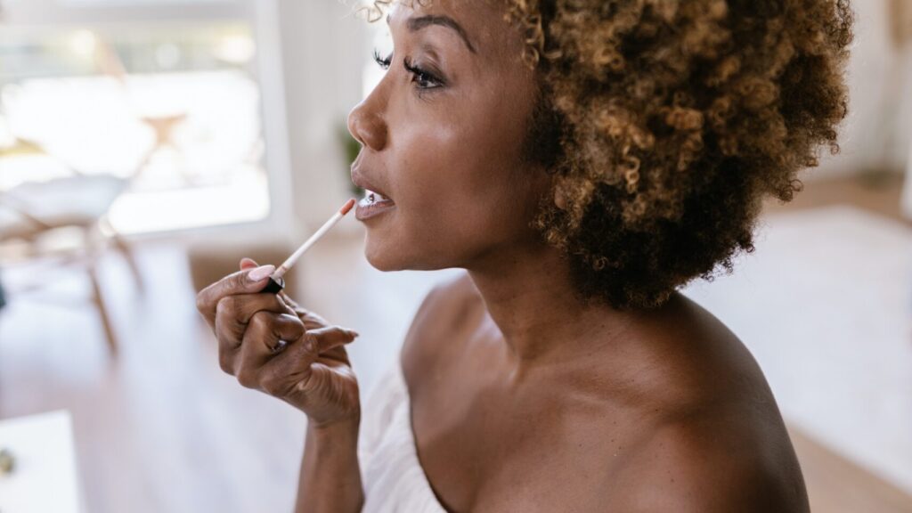 an afro woman applying while looking sideways, as she wears a white dress