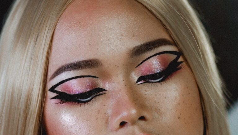 woman with Full coverage makeup and eyelash extensions showing off her eyeliner drawn with eyebrow pencil.