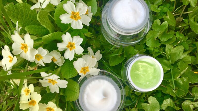 mineral-based serum and cream placed in plants with white flowers.