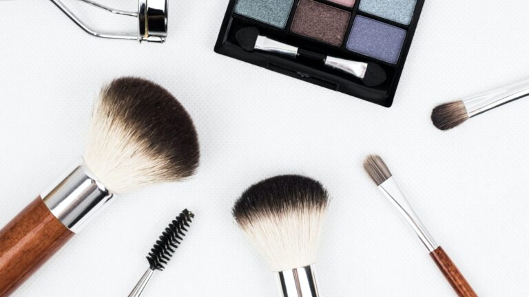 makeup brushes of different sizes and an eyeshadow kit placed on a white background