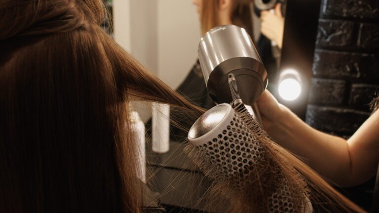 two hands blow drying a womans long hair