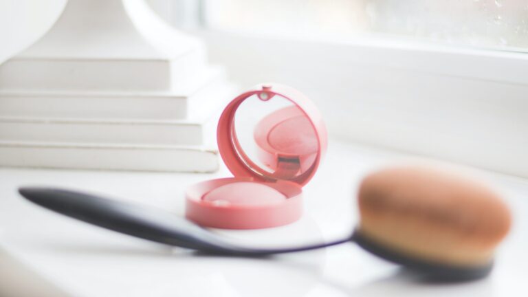 a blush and a beauty blender placed on a white table.