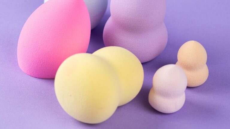 multiple colored and sized beauty blenders placed on a purple background.