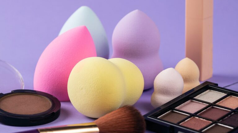 beauty blenders, contour kits and eyeshadow palate all placed on a purple background.