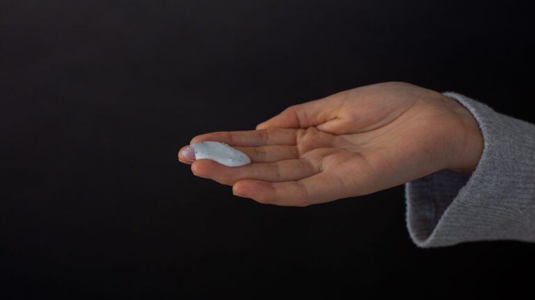 a hand holding white colored anti-aging face serum that is made at home