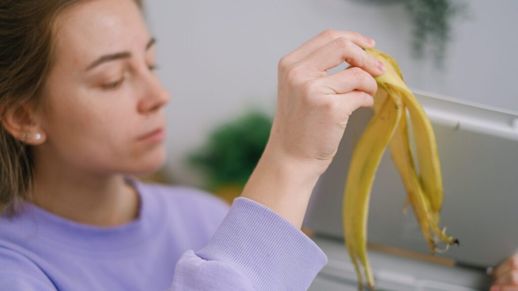 woman in purple shirt holding a banana peel to help her with open pores