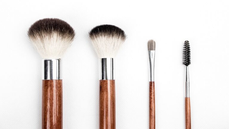 two blush makeup brushes one eyeshadow brush and one spoole placed parallel to each other on a white background