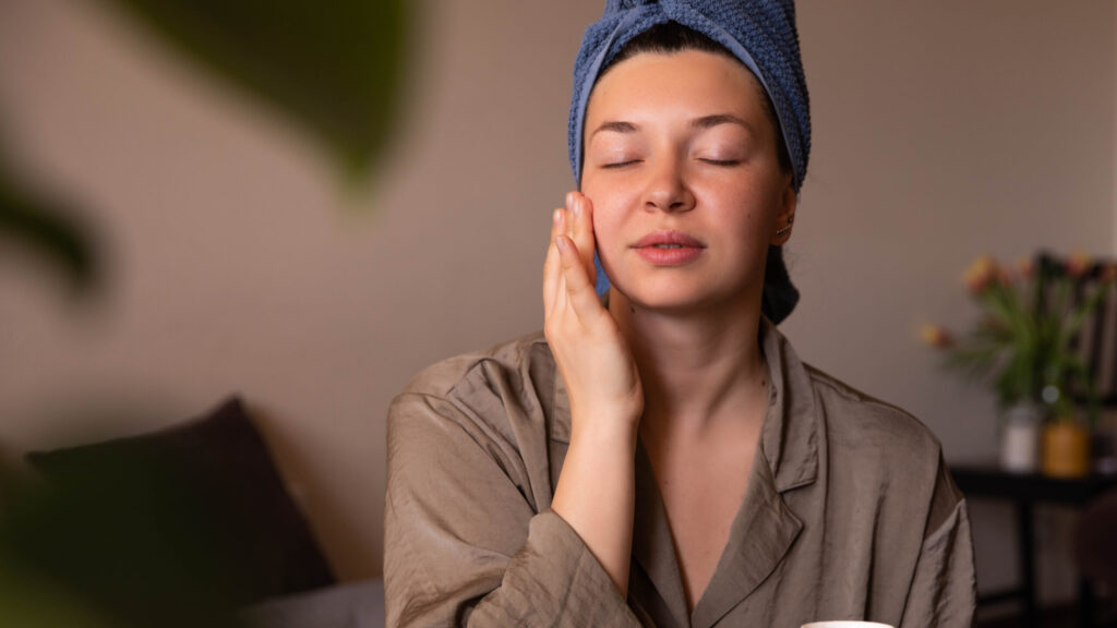 portrait of a woman applying face scrub on her face with her eyes closed