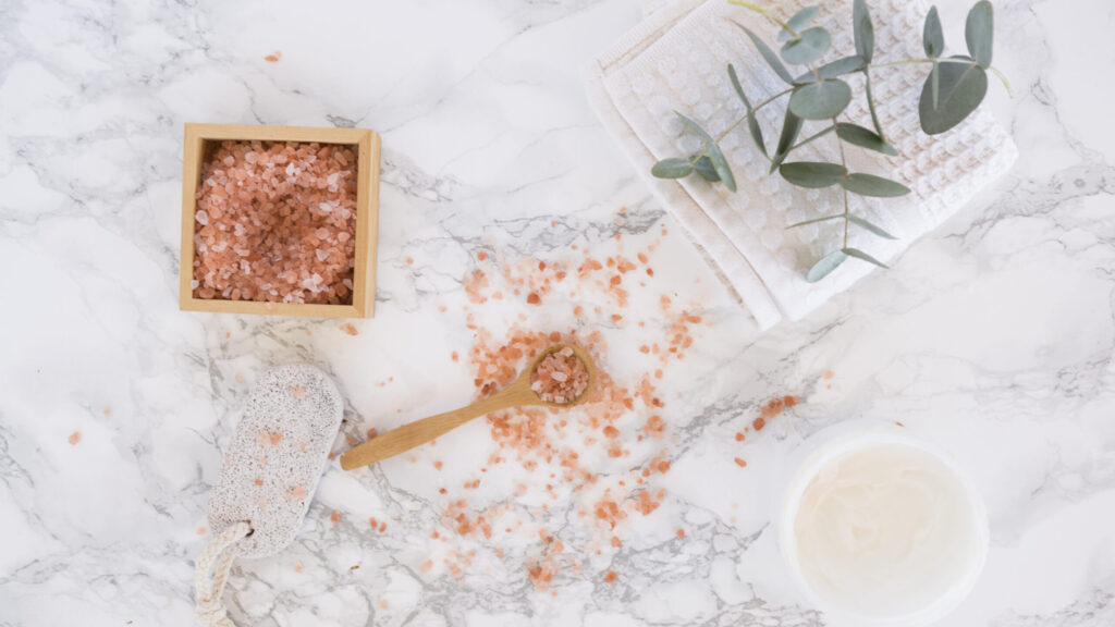 tree hut sugar scrub placed on a marble table. a wooden spoon placed next to it.