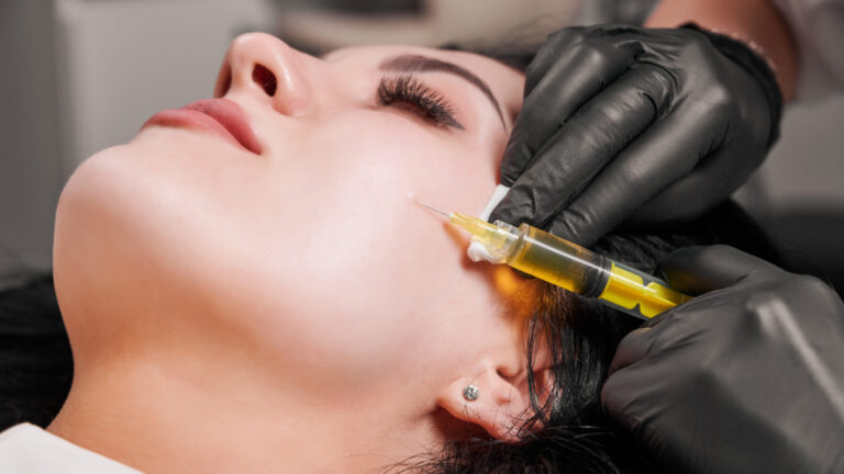 Close-up of micro-needling procedure injection. Doctor cosmetologist beautician in black sterile gloves making injection in female patient face.