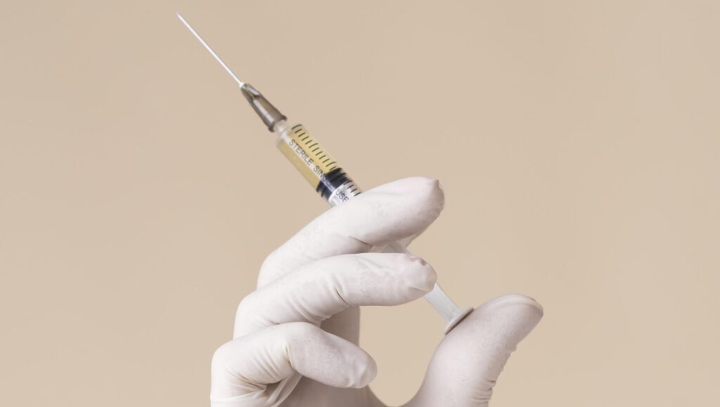 hand with latex glove holding micro-needling syringe