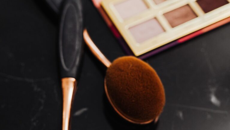 stippling makeup brush placed on a table with black and white table besides a eyeshadow pellate
