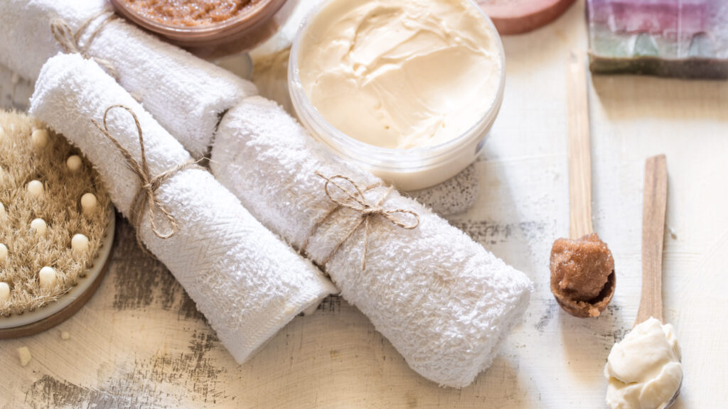 body scrubs placed on a table with towels on a white background