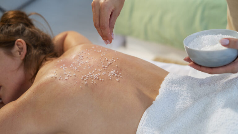 woman laying on a masseuse bed with body scrub on her body